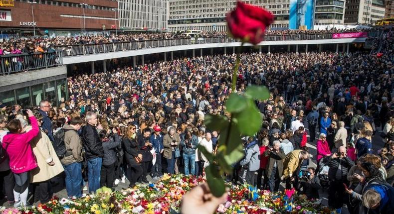 People attend a memorial ceremony on April 9, 2017 at Sergels Torg plaza in Stockholm, close to the point where a truck drove into a department store