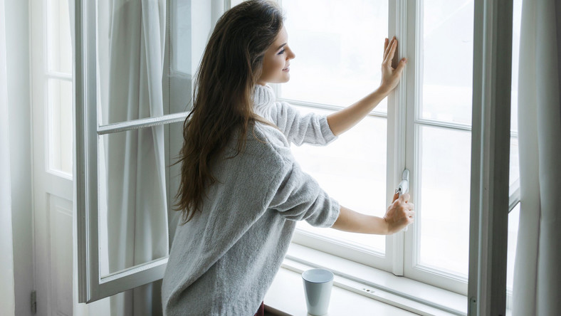 Kobieta otwiera okno, wietrzenie mieszkania