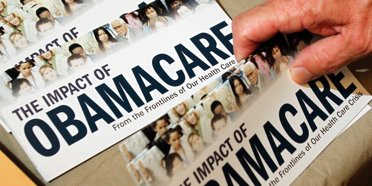 A tea party member reaching for a pamphlet titled "The Impact of Obamacare" at a "Food for Free Minds Tea Party Rally" in Littleton, New Hampshire, in 2012.