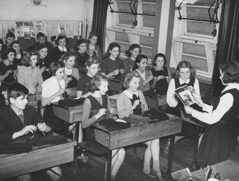 Uczennice i uczniowie w szkole wykonują ubrania dziewiarskie dla załogi łodzi podwodnej, listopad 1941 r.
