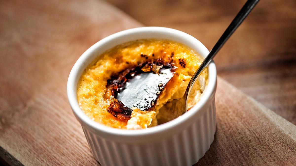 Creme brulee to bardzo charakterystyczny deser na bazie jajek i śmietanki, pokryty cukrową skorupką. Przyciąga miłośników oryginalnych smaków. Żeby zjeść pyszny creme brulee, nie musimy jechać do Hiszpanii lub Francji, gdzie jest najbardziej popularny. Przepis opisujący krok po kroku jego przygotowanie znajdziemy poniżej. Proces jestczas ochłonny, ale umożliwi nam wyczarowanie deseru niczym z drogiej restauracji. Najtrudniejsze będzie oczekiwanie, aż deser się schłodzi, gdyż ciężko opanować chęć zjedzenia go od razu po wyjęciu z pieca. Creme brulee robi wspaniałe wrażenie wizualne, więc idealnie sprawdzi się podawany podczas przyjęć towarzyskich i specjalnych okazji. Przepis na creme brulee wymaga skompletowania tylko kilku łatwo dostępnych produktów. Można wzbogacić go o czekoladę, orzechy lub rodzynki. Sprawdźmy jak zrobić creme brulee we własnym domu.