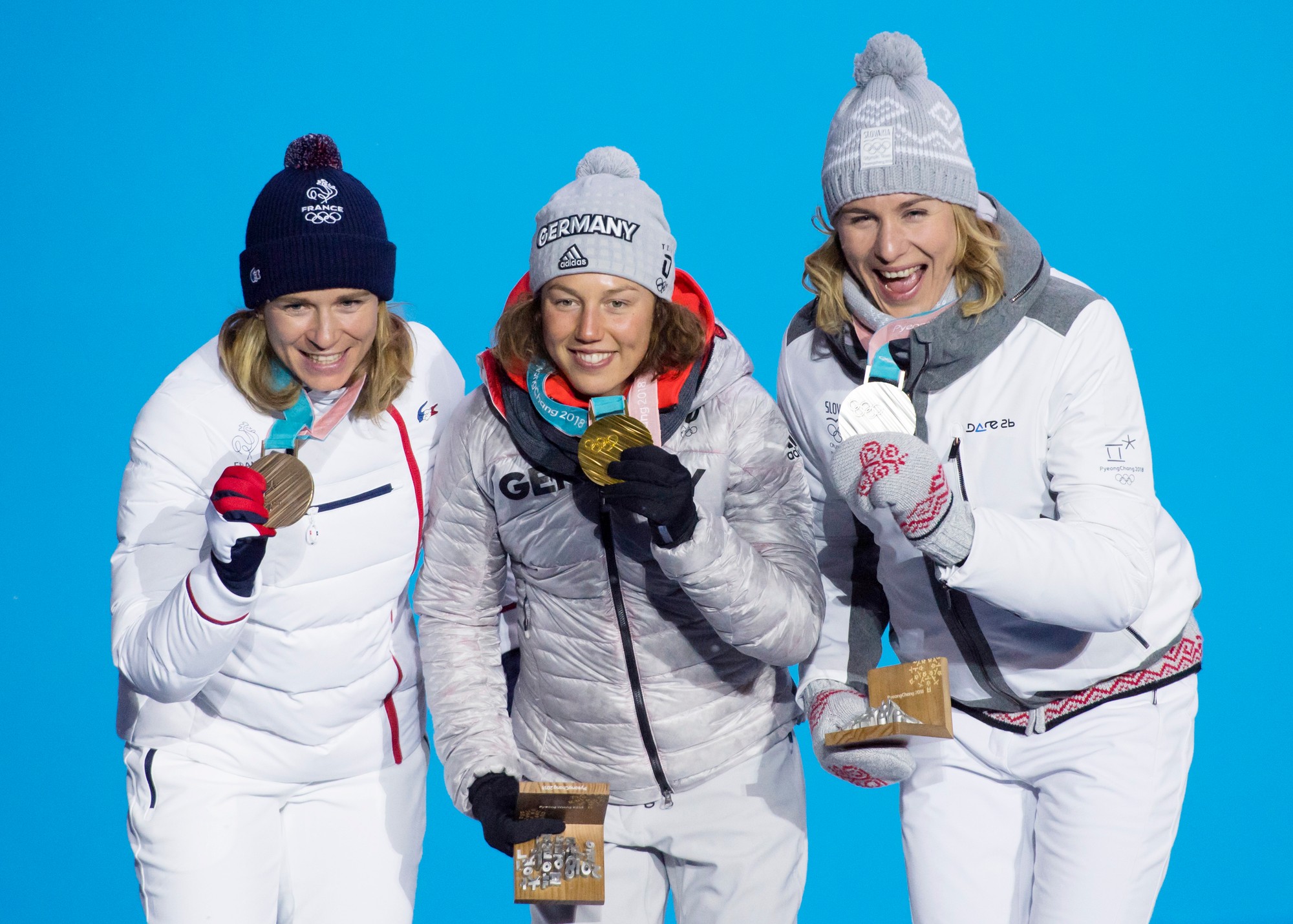 Slovenská biatlonistka Anastasia Kuzminová pózuje so striebornou medailou, ktorú získala na ZOH 2018, uprostred Nemka Laura Dahlmeierová.