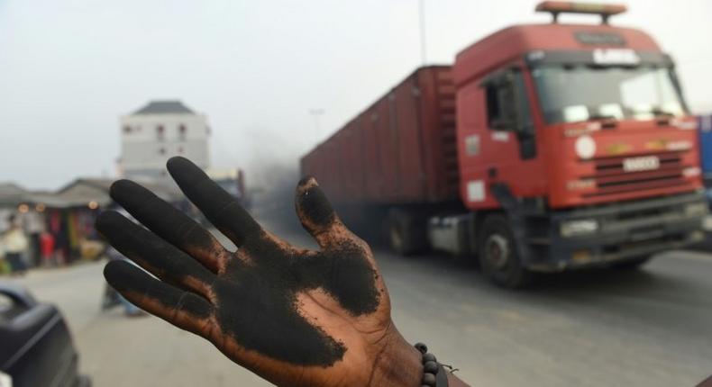 A man holds out his soot covered hand to illustrate how much soot covered the bonnet of his car in Port Harcourt