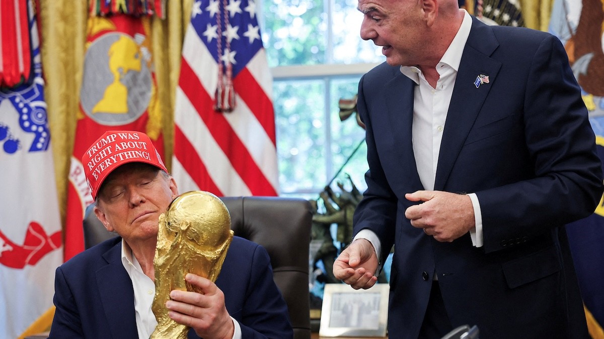 Americký prezident Donald Trump drží trofej z Majstrovstiev sveta vo futbale FIFA a na hlave má šiltovku s napísom „Trump mal vo všetkom pravdu“, kým vedľa neho stojí prezident FIFA Gianni Infantino v Oválnej pracovni Bieleho domu.