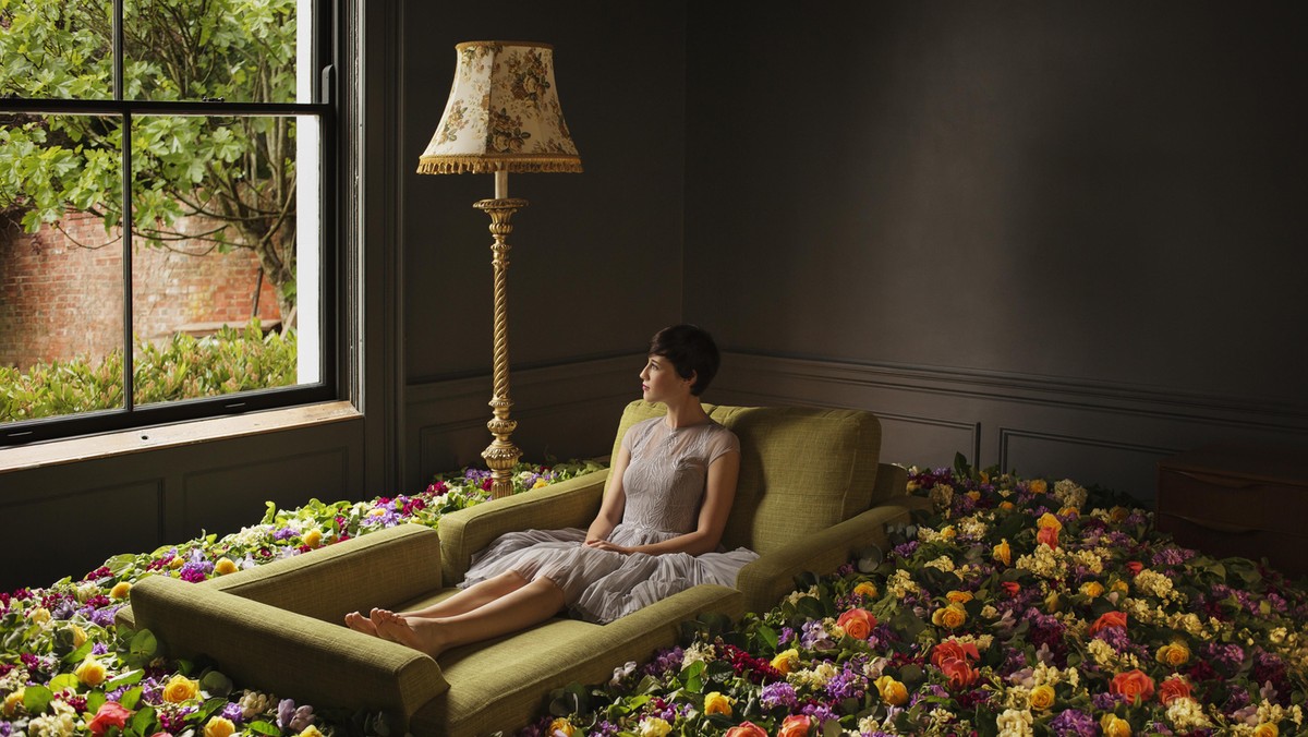 Woman sitting on sofa surrounded by flowers