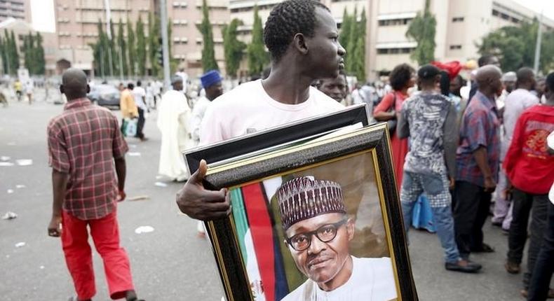 A man holds a framed portrait of Nigeria's President Muhammadu Buhari outside the venue of Buhari's inauguration in Abuja May 29, 2015. REUTERS/Akintunde Akinleye