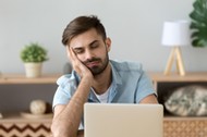 Exhausted man fall asleep near laptop at home workplace