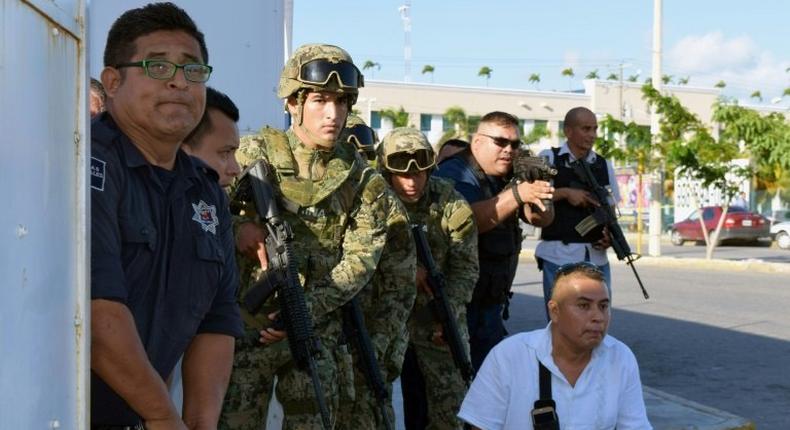 Policemen and soldiers take cover near the building of the Quintana Roo State Prosecution, in Cancun, Mexico, on January 17, 2017