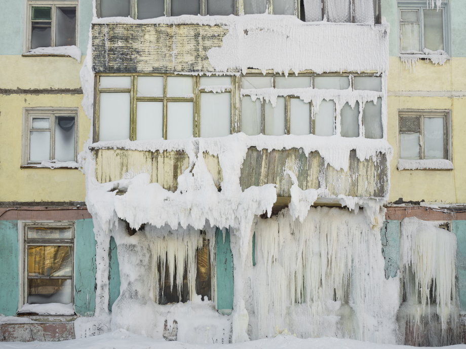 Opuszczone budynki pokrywają się lodem i śniegiem.