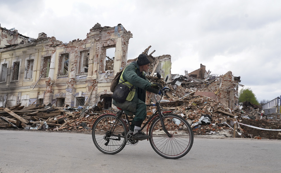 Ukrainiec jedzie na rowerze przez zniszczony po ostrzale Charków