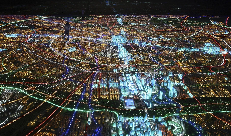 Muškarac (silueta gore levo) hoda iznad džinovskog modela grada Čengdu koji se nalazi u Centru za planiranje provincije Sečuan