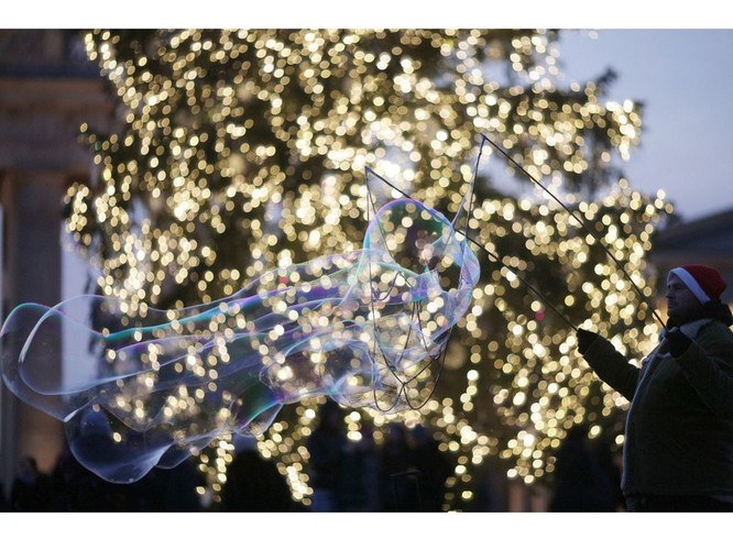 Świątecznie także w Berlinie. Bańki mydlane na tle choinki przed Bramą Brandenburską. Autorem baniek jest Polak, Maks.