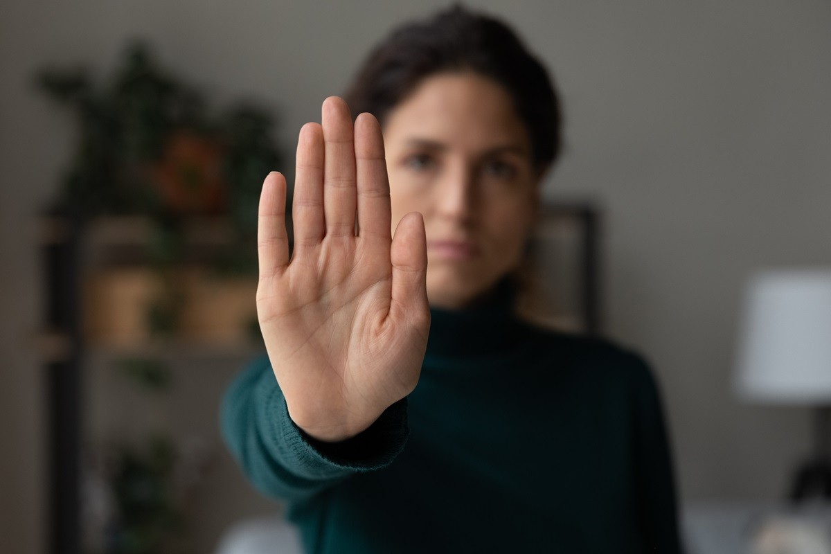 Kobieta wystawia otwartą dłoń przed siebie. Symbolizuje znak "STOP"