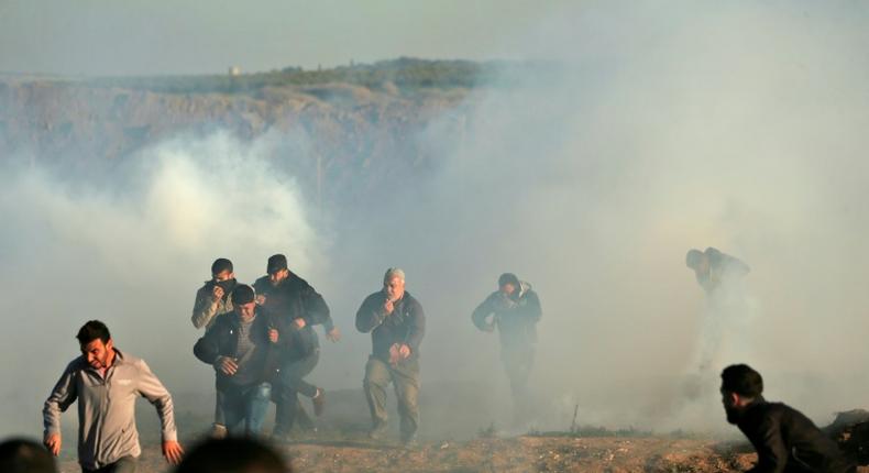 Palestinian protesters run through tear gas fumes during clashes with Israeli forces during a demonstration along the border with Israel east of Gaza City on January 11, 2019