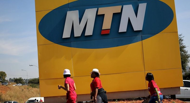 Protesters walk past an MTN logo during a strike of about 2,000 MTN workers outside the company's headquarters in Johannesburg, May 20 2015. REUTERS/Siphiwe Sibeko