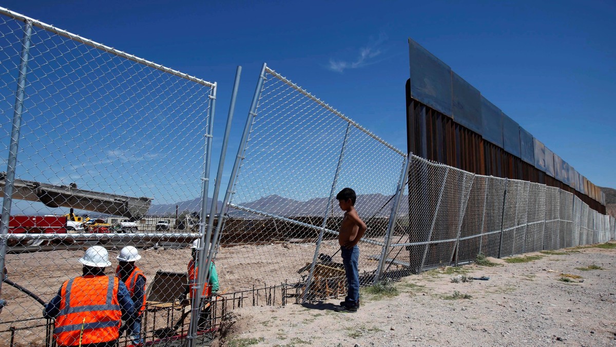 File photo of a boy looking at U.S. workers building a section of the U.S.-Mexico border wall at Sun