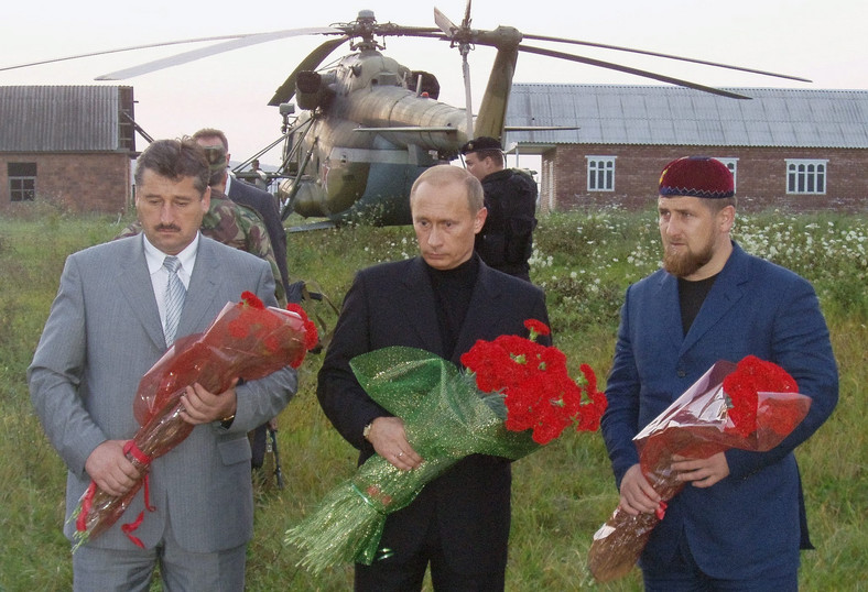Prezydent Rosji Władimir Putin (C), ówczesny czeczeński minister spraw wewnętrznych Ału Ałchanow (L) i  ówczesny wicepremier Czeczenii Ramzan Kadyrow (P) składają kwiaty na grobieKadyrowa w wiosce Centoroj w Czeczenii, 22.08.2004