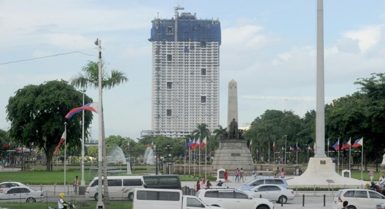 The 49-storey Torre de Manila high-rise condominium looms in the background from the Jose Rizal tomb and monument at Luneta Park in Manila