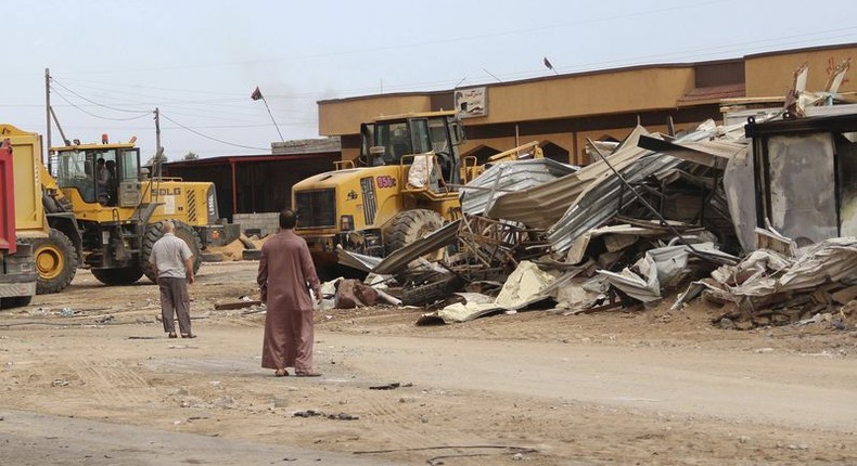 Men watch as bulldozers remove debris in front of a damaged building after a suicide car bomber blew himself up at a checkpoint in Dafniya outside Mistrata, Libya May 31, 2015. REUTERS/Stringer