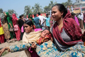 Women help a relative of a garment worker, who went missing in the Rana Plaza collapse, after she fa