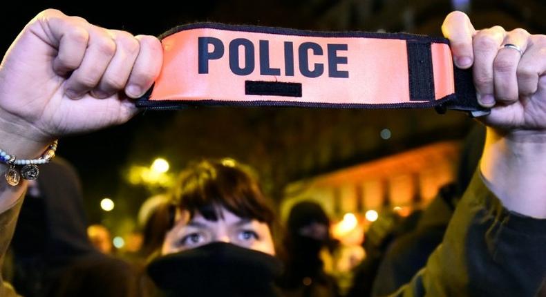 A French police officer holds her armband as she demonstrates in Paris on October 20, 2016