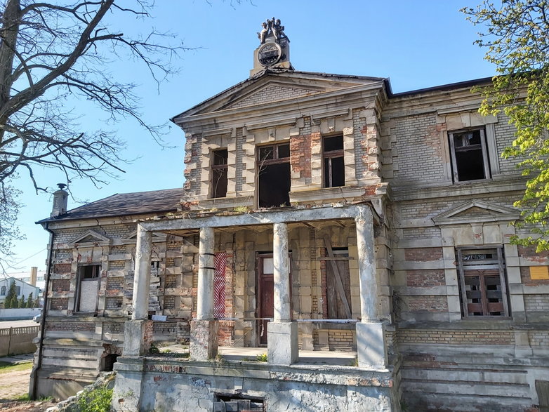 Portyk, a na nim motto rodziny Reymondów, widniejące na tablicy nad portykiem – „Praca jest źródłem powodzenia”.