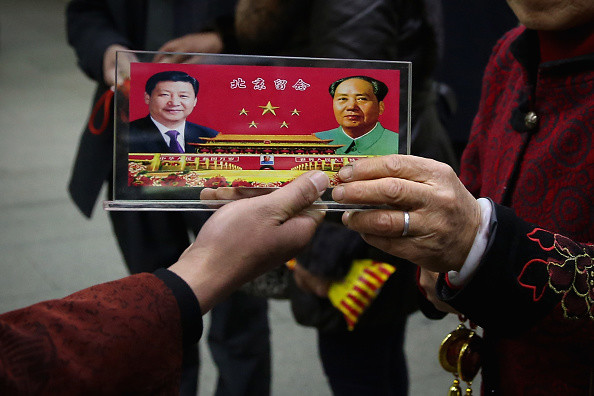 Sprzedawca wystawia pamiątki ze zdjęciami prezydenta Chin Xi Jinpinga i przewodniczącego Mao Zedonga w przejściu podziemnym przed Wielką Halą Ludową. Zdjęcie z 2013 r.