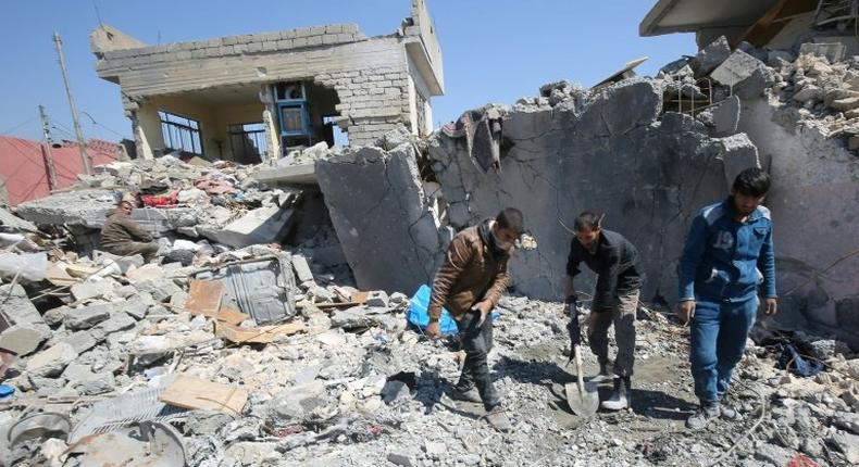 Iraqis clean up the rubble of destroyed buildings in the Mosul al-Jadida area following air strikes that reportedly killed civilians
