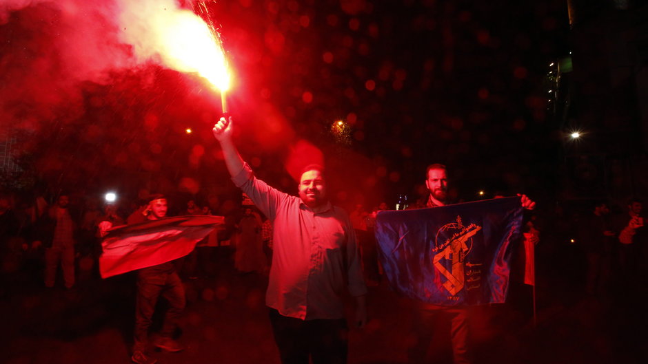 Osoba zapala racę podczas antyizraelskiego wiecu na Placu Palestyńskim w Teheranie w Iranie