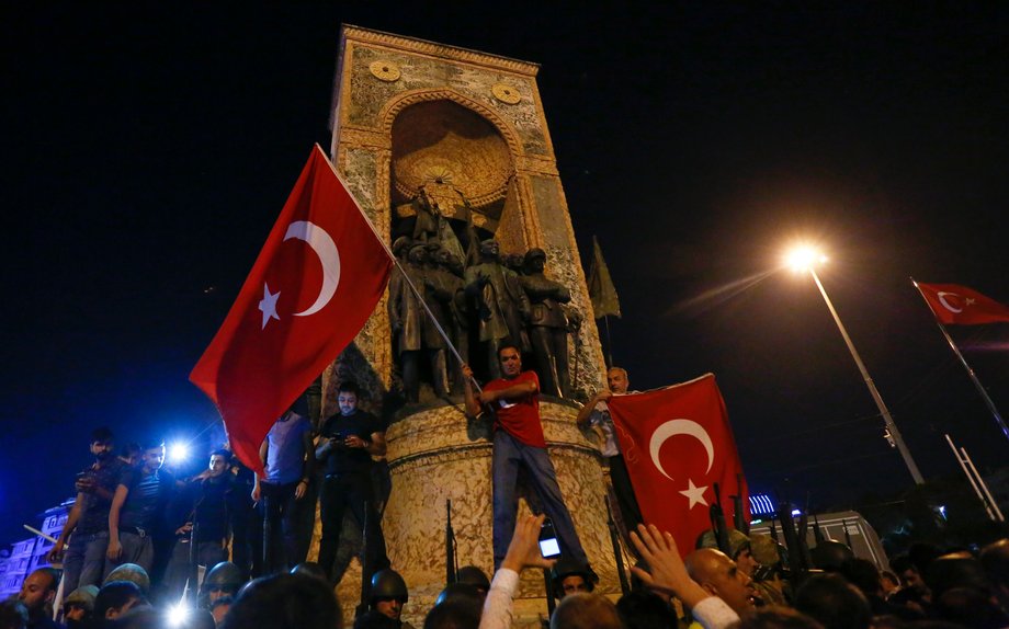 Turkish soldiers stand guard near the Taksim Square as people wave with Turkish flags in Istanbul, Turkey, July 16, 2016.