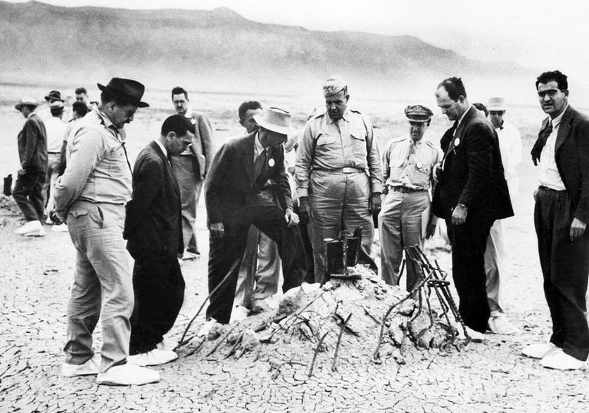 Szef zespołu naukowego i twórca bomy jądrowej Robert Oppenheimer ze stopą na gruzach wieży po eksplozji ładunku „Gadget”. Wizyta miała miejsce 9 września 1945 roku.