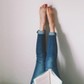 Woman Lying On Bed Reading Book With Legs Raised