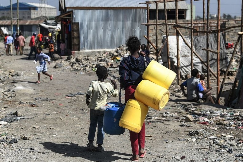 A woman carries jerrycan in search of water on March 10, 2022 as she walks through the Mukuru Kwa Njenga informal settlements. (Photo by SIMON MAINA/AFP via Getty Images)