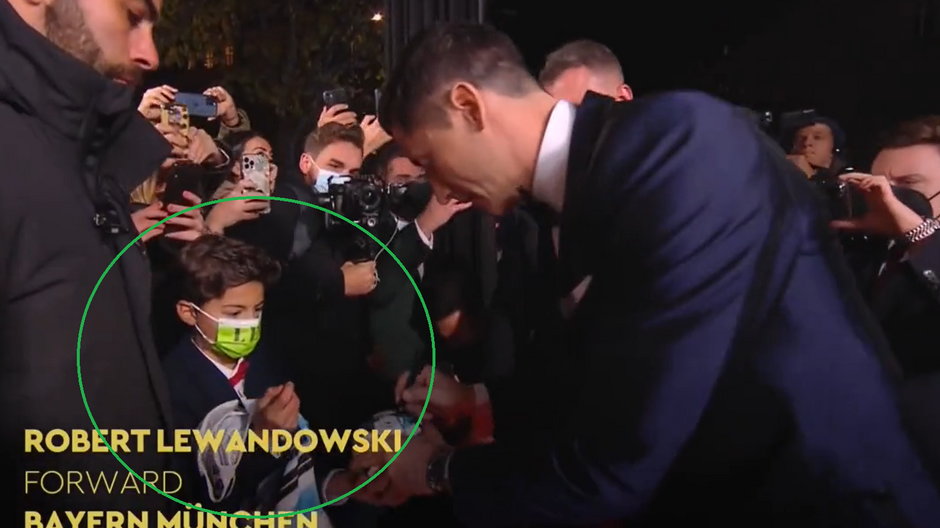 Robert Lewandowski podpisuje piłkę młodemu kibicowi