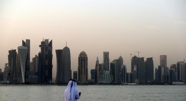 A man looks at his phone on the corniche in the Qatari capital Doha on July 2, 2017