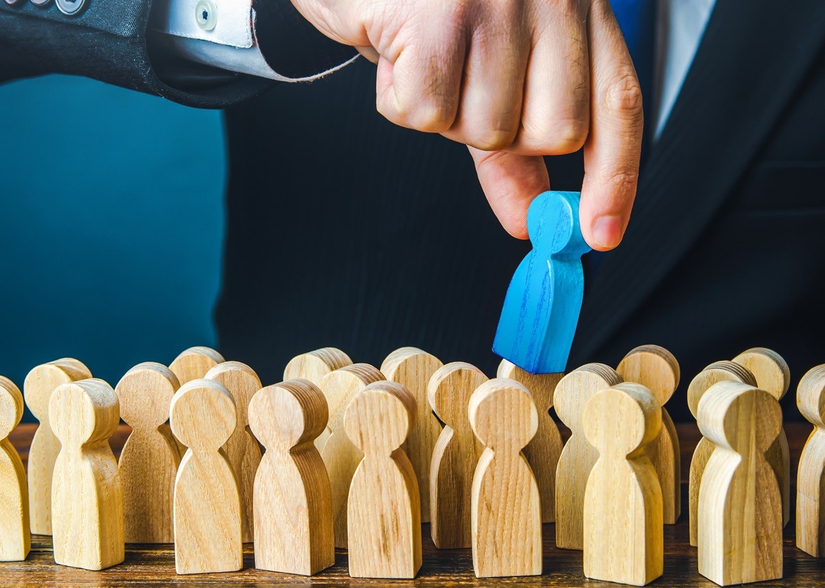 Ręka wyciąga niebieski pionek spośród drewnianych