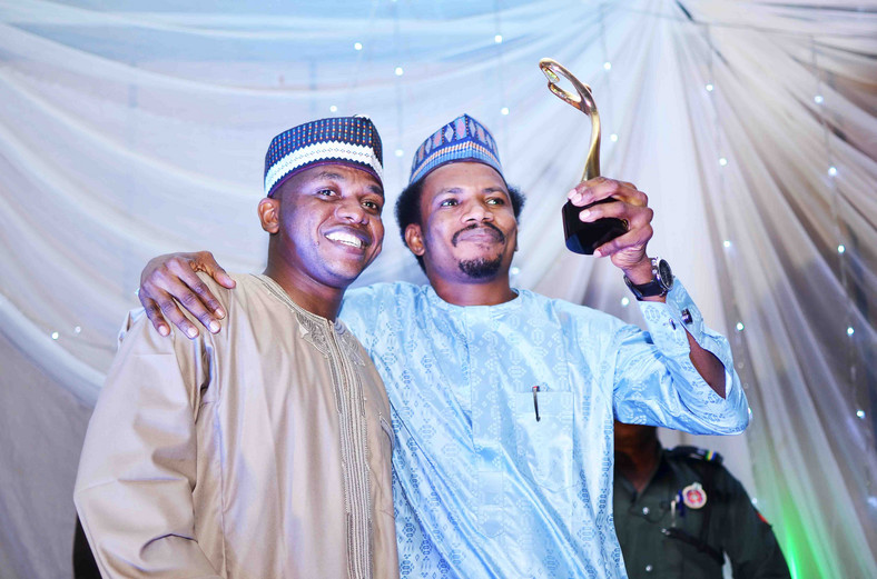 Senator Elisha Abbo (right) raises his "Beacon of Hope" award. "Beacon of Hope" was his campaign slogan before he was elected as the youngest senator in the 9th Senate. Weeks before his inauguration, he beat up and arrested a woman for telling him to calm down during a heated exchange inside a sex toy shop in Abuja [The Gazette Nigeria]