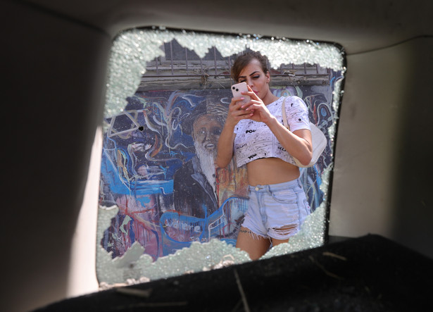 Kobieta fotografuje zniszczony pojazd w Tel Awiwie