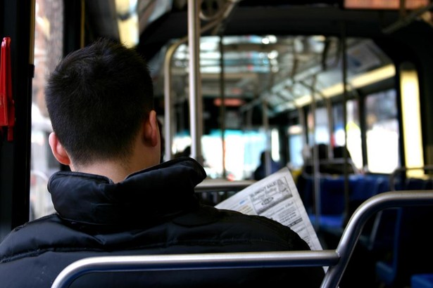 Mężczyzna czytający gazetę w autobusie