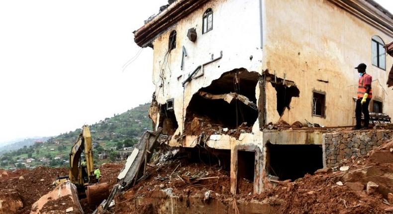 An excavator clears mud and debris after the partial collapse of a hillside in Freetown, Sierra Leone, that swept away hundreds of homes