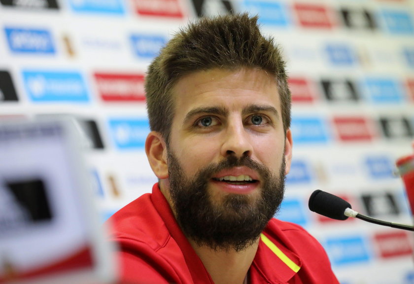 A woman wrapped in an Estelada stands next to an advertisement showing an image of Gerard Pique outs