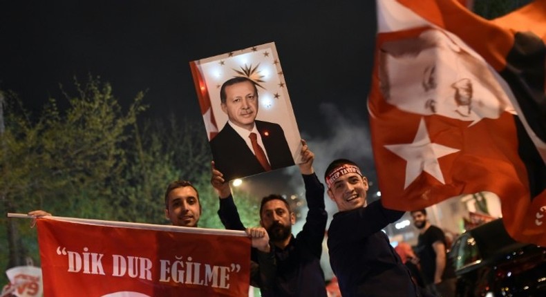 A supporter of the Yes campaign holds up a picture of Turkish president Recep Tayyip Erdogan during a rally near the headquarters of the conservative Justice and Development Party (AKP) in Istanbul on April 16, 2017 after initial results