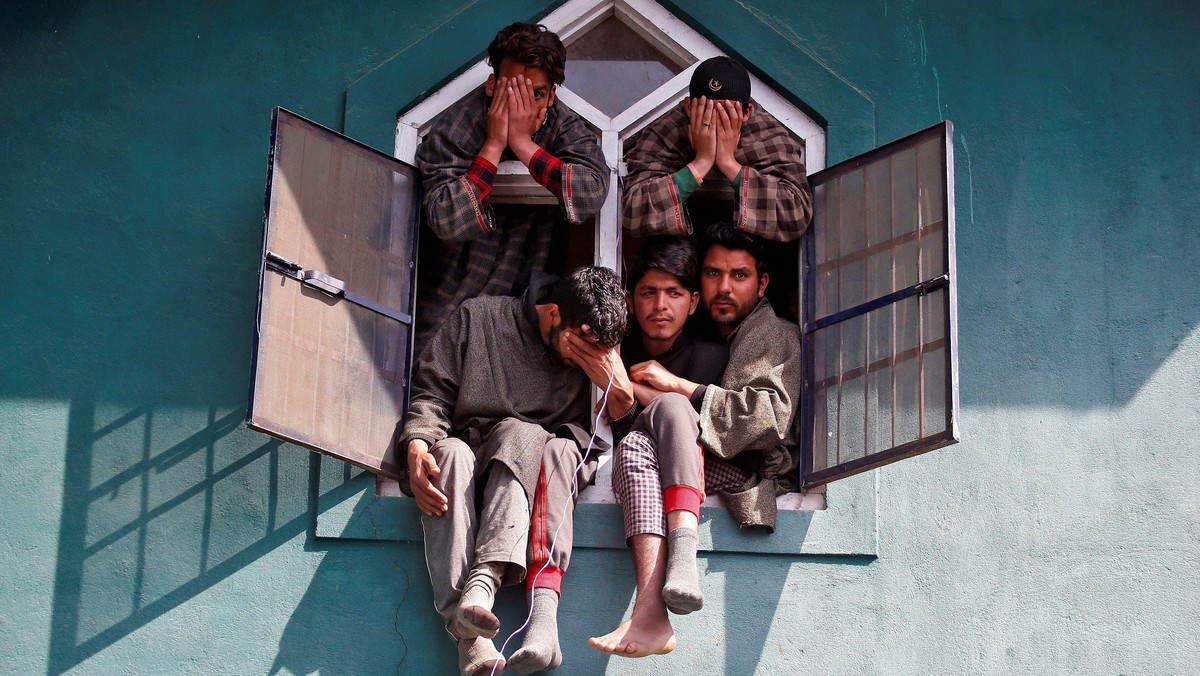 People react as they sit in a window of a mosque during the funeral of Tauseef Ahmad Wagay, a suspec