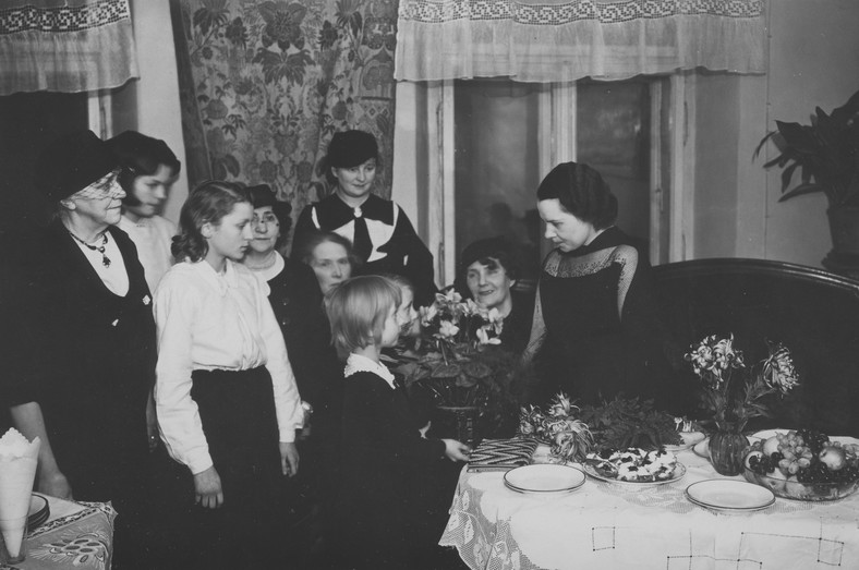 Dzieci wręczają kwiaty pisarce Poli Gojawiczyńskiej. Obok siedzi Zofia Nałkowska