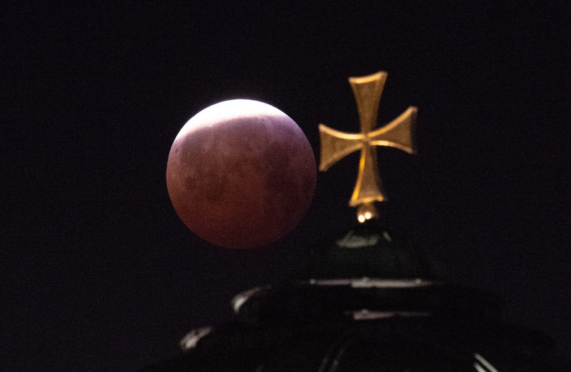 Całkowite zaćmienie Księżyca rozpoczęło się w poniedziałek o godz. 5:41 i trwało do 6:43. W tym czasie Księżyc przybrał barwę czerwoną. Dlaczego tak się dzieje? W trakcie zaćmienia całkowitego Ziemia blokuje docieranie promieni słonecznych bezpośrednio do Księżyca. Jednak nasza planeta ma atmosferę, która załamuje i rozprasza bieg promieni słonecznych. W związku z tym mimo wszystko do Księżyca dociera trochę światła. Jest ono jednak przefiltrowane przez atmosferę, która skuteczniej rozprasza światło o falach krótszych (niebieskie) niż dłuższych (czerwone). Skutki przejścia światła słonecznego przez grubą warstwę atmosfery możemy zobaczyć codziennie na przykład przy zachodzie Słońca – ma ono wtedy kolor czerwony.