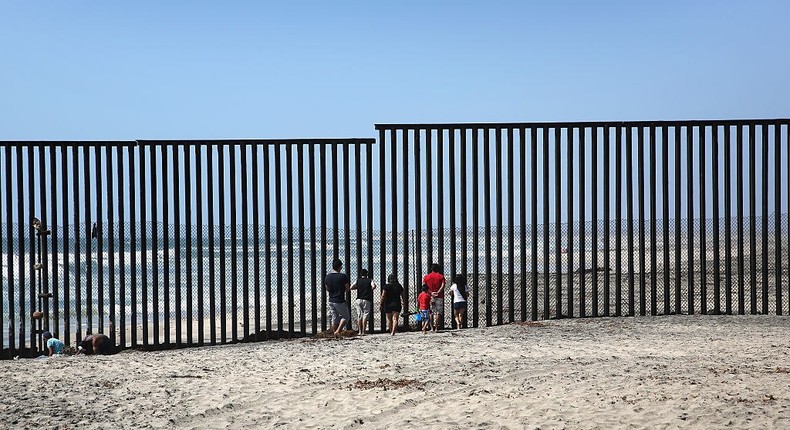 Mexicans stand on the beach while looking through the U.S.-Mexico border fence into the United States on May 1, 2016 in Tijuana, Mexico.