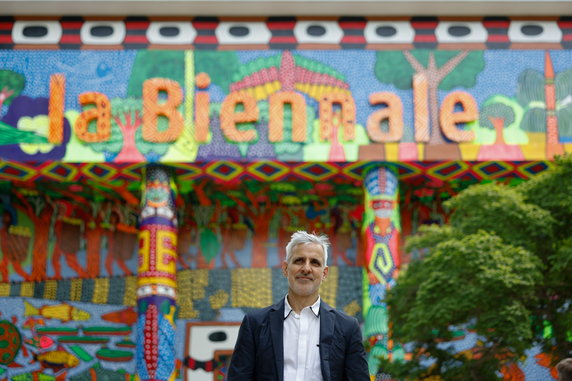 Kurator wystawy Adriano Pedrosa i fasada pawilonu centralnego ozdobiona malarstwem artystów z Amazonii