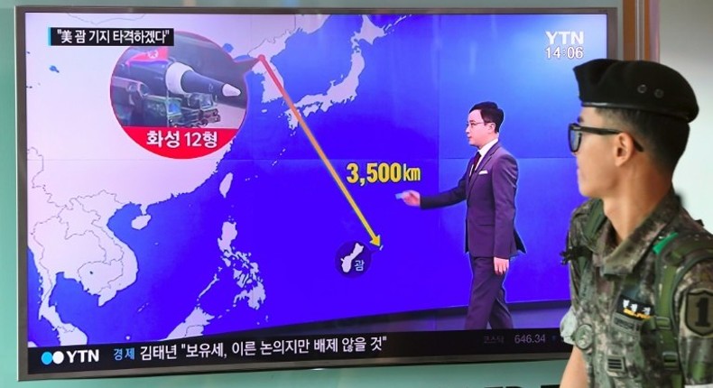 A South Korean soldier walks past a television screen showing a graphic of the distance between North Korea and Guam at a railway station in Seoul