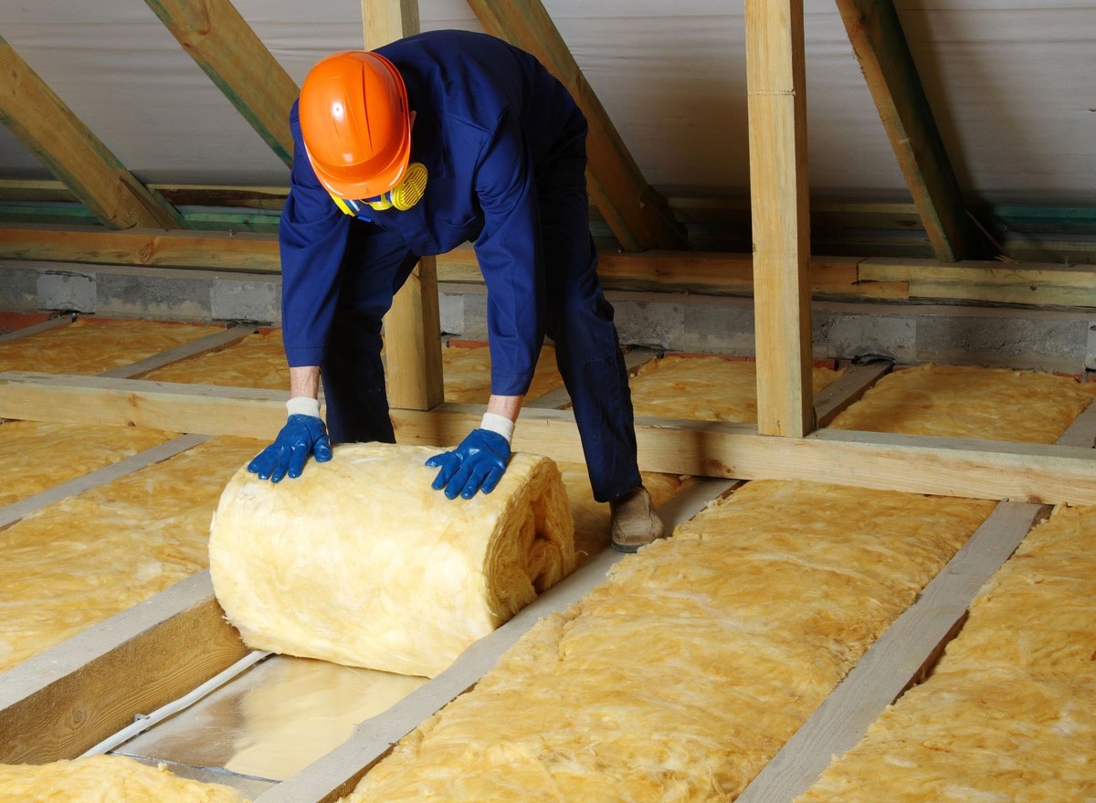 mężczyzna wykłada poddasze wełną