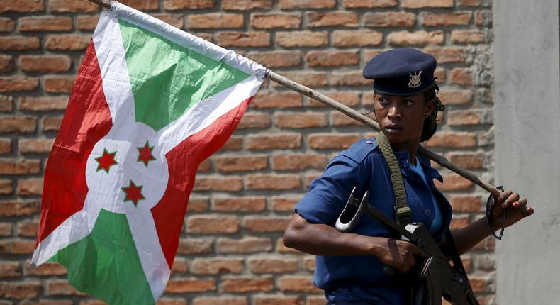 A policewoman carries a Burundi flag during a protest against President Pierre Nkurunziza's decision to run for a third term in Bujumbura, Burundi, May 29, 2015. REUTERS/Goran Tomasevic